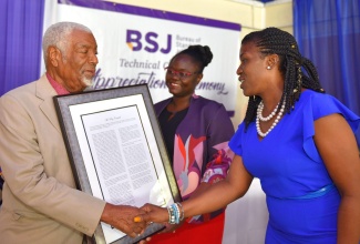 Chief Technical Director in the Ministry of Industry, Commerce, Agriculture and Fisheries, Monique Gibbs (right), congratulates Chairman of the Bureau of Standards Jamaica's (BSJ) Electrical Practices and Products Technical Committee, Ray Campbell (left), who was among 115 volunteers honoured by the BSJ, during a ceremony on Wednesday (Oct. 17), at the Terra Nova Hotel in St. Andrew. Looking on is BSJ’s Standards Development Officer, Sherieka Satchell Knight.