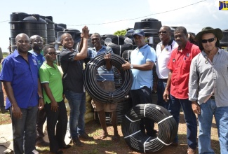 State Minister in the Ministry of Industry, Commerce, Agriculture and Fisheries, Hon. Floyd Green (4th left), presents Leroy Gayle (centre), one of the farmers affected by fire in Flagman, St. Elizabeth, with irrigation hoses, during a presentation ceremony at the Pedro Plains Anglican Church hall in the parish, on Friday (October 18). Others (from left) are: Permanent Secretary in the Ministry of Industry, Commerce, Agriculture and Fisheries, Dermon Spence; Principal Director, Field Services and Operations, Rural Agricultural Development Authority (RADA), Winston Simpson; Acting Principal Finance Officer in the Ministry, Ann-Marie Tomlinson; Chief Executive Officer, RADA, Peter Thompson; Chief Technical Director in the Ministry, Dr. Roy McNeil; RADA St. Elizabeth Parish Manager, Nathan Samuels; and farmer, Ian Dowell.