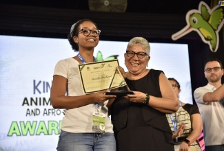 First-Place winner in the Best Character Design Category at KingstOOn 2019, Danielle Parchment (left) is presented with her winning prize by Chief Technical Director Planning, Monitoring and Evaluation Division, in the Office of The Prime Minister, Jacqueline Lynch-Stewart in April. 