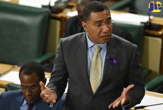 Prime Minister, the Most Hon. Andrew Holness, addresses the House of Representatives on Tuesday (November 26).  Seated at left is Minister of Finance and the Public Service, Dr. the Hon. Nigel Clarke.