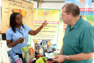 Minister of Industry, Commerce, Agriculture and Fisheries, Hon. Audley Shaw (right), listens to   Animal Health Technician at the Ministry, Sharna Frater,  at an Open Day staged by the Ministry’s Food Storage and Prevention of Infestation Division (FSPID), at Hope Gardens, in St. Andrew, on October 31.