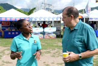 Minister of Industry, Commerce, Agriculture and Fisheries, Hon. Audley Shaw (right), listens to Acting Storage Officer, Food Storage and Prevention of Infestation Division (FSPID), Tamara Moore, at a recent open day held at the Ministry's Hope Gardens headquarters in St. Andrew.

