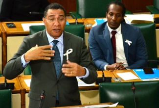 Prime Minister, the Most Hon. Andrew Holness, delivers a statement in the House of Representatives on November 19. Listening (at right) is State Minister in the Ministry of Education, Youth and Information, Hon. Alando Terrelonge.

