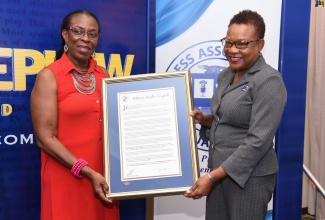 Acting Deputy Chief Executive Officer, Jamaica Information Service (JIS), Enthrose Campbell (right), receives a citation from Director, Press Association of Jamaica (PAJ), R. Christene King,  at the PAJ Veterans’ Luncheon held at the Courtyard by Marriott, New Kingston, on November 20. 