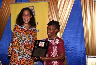 RAF 2485: Chief Executive Officer of the Jamaica Information Service (JIS), Mrs. Donna-Marie Rowe (left), presents a plaque to retiree, Ms. Dolet McPherson, for 14 years of dedicated service to the JIS, at its Christmas Soiree, held  at the Terra Nova Hotel, in Kingston, on Saturday (December 7).