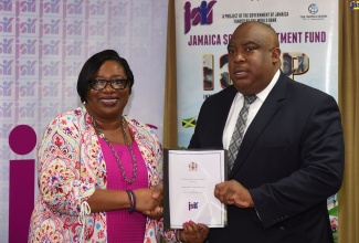 Social Development Manager, Jamaica Social Investment Fund (JSIF), Mona Sue-Ho (left), presents Acting Deputy Commissioner of Police, Richard Stewart, with a signed copy of a memorandum of understanding (MOU) between the entities, for the provision of additional funding for the Jamaica Crime Observatory (JCO) Enhancement Project. The signing was held on Wednesday (January 22) at the JSIF's corporate offices, Kingston.