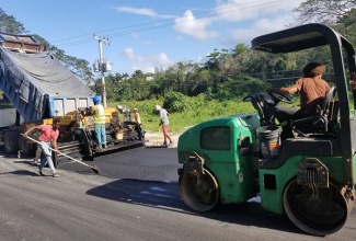 Workers apply asphalt to a section of the Fairfield Bridge to Taylor Avenue roadway.