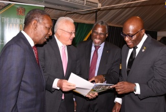 Justice Minister, Hon. Delroy Chuck (second left), peruses a copy of the first ever Strategic Business Plan for the Judicial Arm of Government, during the document's launch at the Terra Nova Hotel, in Kingston, on Friday (January 31). Also viewing the document (from left) are: President of the Court of Appeal, Hon. Dennis Morrison;  Trinidad and Tobago Attorney-at-Law and Economist, Dr. Terrence Farrell; and Chief Justice, Hon. Bryan Sykes.