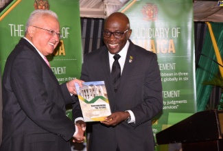 Justice Minister, Hon. Delroy Chuck (left), is presented with a copy of the Judiciary’s Strategic Business Plan, titled ‘Benchmarking the Future: Courting Success’, by Chief Justice, Hon. Bryan Sykes, during the document’s recent launch, at the Terra Nova All-Suite Hotel in St. Andrew. Mr. Chuck represented Prime Minister, the Most Hon. Andrew Holness.