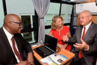 Justice Minister, Hon.  Delroy Chuck (right), in discussion with (from left) Executive Director of the Legal Aid Council, Hugh Faulkner, and Canada’s High Commissioner to Jamaica, Her Excellency Laurie Peters. They are seated inside one of two new Mobile Justice Units provided through a joint partnership involving the Governments of Jamaica and Canada, and the United Nations Development Programme (UNDP).