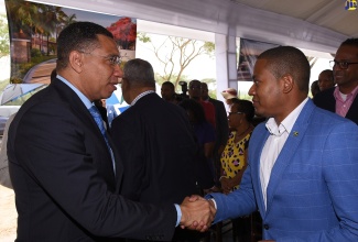 Prime Minister, the Most Hon. Andrew Holness (left), greets Minister of State in the Ministry of Industry, Commerce, Agriculture and Fisheries, Hon. Floyd Green, during the ceremony to break ground for a US$1-billion multi-resort development – Sugar Cane Bay Jamaica – in Llandovery, St. Ann, on February 28.