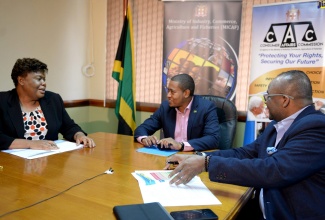 ave Reid Photo

State Minister in the Ministry of Industry, Commerce, Agriculture and Fisheries, Hon. Floyd Green (centre), engages with Chief Executive Officer of the Consumer Affairs Commission (CAC), Dolsie Allen (left),  during at virtual press briefing on Friday (May 22), to outline details of the Government's compensation to motorists, who were affected by the use of contaminated fuel in 2015. Looking on at right is Chairman of the CAC, Donovan White.