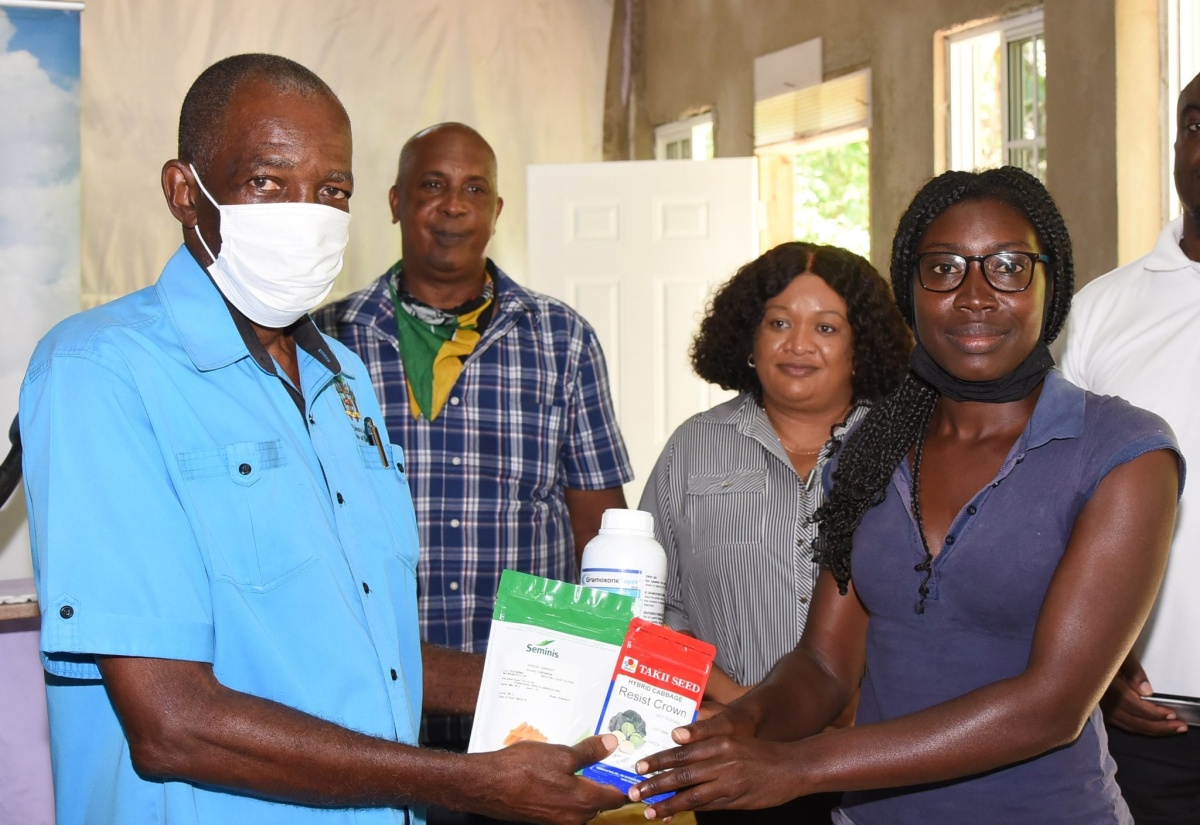 Minister without Portfolio in the Ministry of Industry, Commerce, Agriculture and Fisheries, Hon. J.C. Hutchinson (left), presents young farmer, Okelia Douce (right), with agricultural inputs at an agricultural forum held yesterday (June 11), at the Seventh-day Adventist Church of God in Dunkeld, St. Catharine. Sharing the moment (from second left) are Chairman of the Rural Agricultural Development Authority (RADA) St. Catherine Parish Advisory Committee, William Cital, and RADA Parish Manager, Ruth Barrett.

