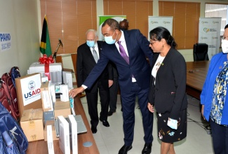 Minister of Health and Wellness, Dr. the Hon. Christopher Tufton  (second left), looks at pieces of equipment donated by the Pan American Health Organization (PAHO) and the United States Agency for International Development (USAID), during a handover ceremony on Tuesday (June 16), at the Ministry’s New Kingston offices in St. Andrew. Looking on (from left) are United States Ambassador to Jamaica, Donald Tapia, Chief Medical Officer (CMO), Dr. Jacquiline Bisasor-McKenzie; and Representative of the Pan American Health Organization (PAHO) to Jamaica, Dr. Bernadette Theodore-Gandi.