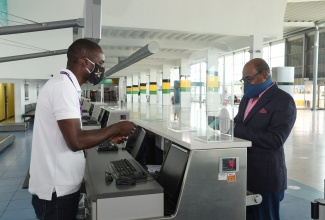 Andre Lewis, Operations Manager, PAC Kingston assists Minister of Tourism, Hon. Edmund Bartlett (right) as he examines one of the many new plexiglass screens that have been installed at the Norman Manley International Airport to help reduce the spread of COVID-19. Minister Bartlett toured the facility recently to examine the level of preparedness for the reopening of the nation’s borders to tourists on June 15, 2020. The Minister expressed satisfaction with the measures that have been put in place to safeguard front-line workers and passengers alike, including the installation of numerous automated hand sanitizing stations, decals to facilitate social distancing and a quarantine area. 