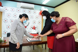 Chief Medical Officer, Dr. Jacquiline Bisasor-McKenzie (left), joins Director of the National Public Health Laboratory (NPHL), Dr. Michelle Hamilton (centre), and Acting Director, National Blood Transfusion Service (NBTS), Dr. Alisha Tucker, in cutting a cake at the World Blood Donor Day awards ceremony held ​on Monday (June 15), at the NBTS's Slipe Pen Road address, Kingston. 