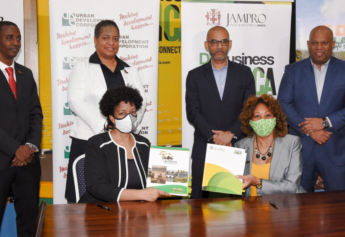 Urban Development Corporation (UDC) General Manager, Heather Pinnock (left, seated), and President of Jamaica Promotions Corporation (JAMPRO), Diane Edwards (right, seated), display copies of the signed memorandum of understanding (MOU) between the entities that will facilitate their collaboration on programmes and initiatives, aimed at leveraging the UDC’s assets and engagements to generate local and international investments, and create business development opportunities in Jamaica. The signing took place at JAMPRO’s Corporate Office in New Kingston, on Wednesday (June 17). Also attending were (from left) UDC Deputy General Manager, Finance, Treasury and Investment, Omar Gray; Deputy General Manager, Subsidiary Management, UDC, Lisa Golding; and JAMPRO Vice Presidents for Marketing, Gabriel Heron, and Sales and Promotions, Norman Naar.