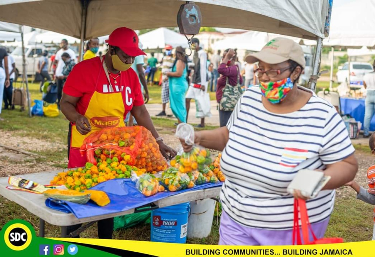 A Kingston and St. Andrew pepper farmer (left), prepares her produce for display, while a customer leaves with her purchase of peppers, at the recently held Social Development Commission Business Fair and Farmers’ Market in Duhaney Park, St. Andrew.

