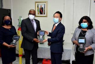 Former Minister without Portfolio in the Ministry of Economic Growth and Job Creation, with responsibility for Land, Environment and Climate Change, Hon. Leslie Campbell (second left), is presented with a Leica CS20 field controller by Chargé d’Affaires, Embassy of the Republic of Korea, Lim Baejin (second right), during the official handing over ceremony for several pieces cadastral mapping and land surveying equipment, on Thursday (July 16) at the National Land Agency Estate Management Division, Downtown, Kingston. Also displaying the devices are Chief Executive Officer, National Land Agency (NLA) Elizabeth Stair (left) and Under-Secretary, Bilateral, Regional and Hemispheric Affairs in the Ministry of Foreign Affairs and Foreign Trade, Ambassador Janice Miller.  Mr. Campbell has since been re-assigned to the Ministry of Industry, Commerce, Agriculture and Fisheries.

