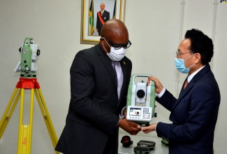 Minister without Portfolio in the Ministry of  Economic Growth and Job Creation, with responsibility for Land, Environment and Climate Change, Hon. Leslie Campbell (second left), is presented with a Leica CS20 field controller by Chargé d’Affaires, Embassy of the Republic of Korea, Lim Baejin, at the official handover of cadastral mapping and land surveying equipment, on Thursday (July 16), at the National Land Agency Estate Management Division, downtown Kingston.

