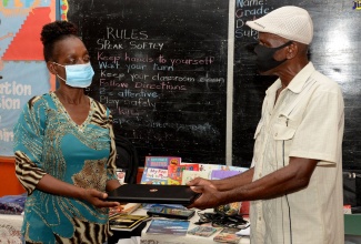 Contact person for the United Kingdom (UK)-based New Direction Christian Fellowship, Leslie Washington (right), presents Acting Principal of the Kitson Town Primary School, Janice Yates, with one of two laptop computers, donated to the school at a handover ceremony at the institution, on August 17. The educational gifts consist of several personal items for students and scores of books for the school and the Kitson Town Library.