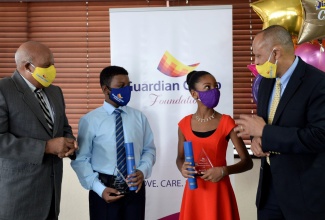 President of Guardian Life Limited, Eric Hosin (right), speaks with top-performing girl and boy in the Primary Exit Profile (PEP) Abigail McKenzie (second  right) and Chad Wright (second left), during the Guardian Group Foundation’s annual Scholarship and Grant Awards ceremony held on Wednesday (August 12), at the company's corporates office in New Kingston. Sharing the moment is Chairman of the Guardian Group Foundation, Gladstone Lewars. The students have been awarded scholarships valued at $1 million each,  payable at $200,000 per annum over five years.

