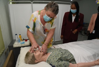 Director, Mona Ageing and Wellness Centre, Professor Denise Eldemire-Shearer (left), conducts a medical examination demonstration on a dummy, during a tour of the Strategic Management and Training Consultants Ltd. (SMTC) Career Institute, today (September 10). This followed the signing of an MOU by the SMTC Career Institute and the Mona Ageing and Wellness Centre on the development and delivery of an advanced Patient Care Technician Certificate training course. Observing is Principal, Strategic Management and Training Consultants Ltd (SMTC) Career Institute, Beverley Dinham Spencer.

