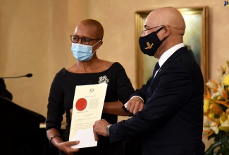 Governor-General, His Excellency the Most Hon. Sir Patrick Allen (right), presents the Instrument of Appointment to new Minister  of Education, Youth and Information, Hon. Fayval Williams, at a swearing-in ceremony at King's House on Sunday (September 13).