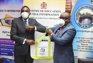 Minister of State in the Ministry of Education, Youth and Information, Hon. Robert Morgan (left), is presented with a gift bag by Director for the Ministry’s Access to Information Unit, Damian Cox, during Monday’s (September 28) digital launch of the Government’s Records and Information Management (RIM) Programme Implementation for the third cohort of ministries, departments and agencies (MDAs) being targeted under the initiative. The Programme’s implementation is being led by the Jamaica Archives and Records Division (JARD), an agency of the Ministry of Education, Youth and Information, with support from the Cabinet Office.


