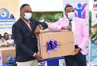 Managing Director of the Jamaica Social Investment Fund (JSIF), Omar Sweeney (left), presents Chief Executive Officer, Registrar General's Department  (RGD), Charlton McFarlane, with a laptop computer during the handover of information and communications technology (ICT) equipment on Tuesday (September 22), at the RGD headquarters in St. Catherine.

