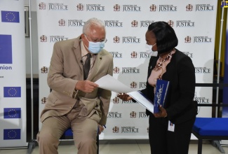 Minister of Justice, Hon. Delroy Chuck (left), consults with Coordinator, Restorative Justice, Ministry of Justice, Adrienne Lindsay, during the Access to Justice Virtual Town Hall Meeting, on October​ 21.
