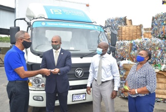 Minister of Housing, Urban Renewal, Environment and Climate Change, Hon. Pearnel Charles Jr. (third left), observes as Chairman, Recycling Partners of Jamaica Limited (RPJ), Damien King (left), accepts keys for a box truck from Acting Executive Director, Tourism Product Development Company (TPDCo.), Stephen Edwards, during the handover ceremony,  on Wednesday (October 21), at the recycling company’s Lake’s Pen address in St. Catherine.  At right is Chief Financial Officer,  RPJ, Wincella Cummings.

