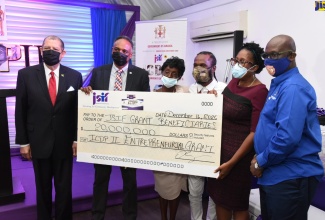 Minister of Industry, Investment and Commerce, Hon. Audley Shaw (left), shares in the symbolic handover of a cheque valued at $20 million by the Jamaica Social Investment Fund (JSIF) to benefit community entrepreneurs under the Enterprise Development Project. Others from (second left) are Managing Director, JSIF, Omar Sweeney; beneficiaries Lorna Green and Shawn Castell; Opposition Spokesperson on Education and Training, Dr. Angela Brown Burke; and Minister of Local Government and Rural Development, Hon. Desmond McKenzie. Occasion was the official launch of the project at the Spanish Court Hotel in New Kingston on December 16.

