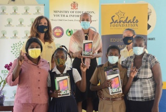 Minister of Education, Youth and Information, Hon. Fayval Williams (back row, centre), shows off one of the 28 tablets donated by the Sandals Foundation for grade-six students of the Ocho Rios Primary School, during a ceremony at the institution on December 4. She is joined by Director of Operations at Sandals Foundation, Karen Zacca (back row, left); and Sandals Resorts Regional Public Relations Manager Lyndsay Isaacs (back row, right). In the front row (from left) are Sharon Bailey and her daughter Ashley Bailey; and Antonio McDuffus and his mother, Angelene Palmer.

