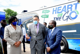 Prime Minister, the Most Hon. Andrew Holness (centre), speaking with Managing Director, HEART/NSTA Trust, Dr. Janet Dyer (left); and Chairman, Board of Directors, HEART/NSTA Trust, Edward Gabbidon, after a tour of the agency's new  Mobile Training Unit, which was launched on Wednesday (December16)  at Garmex Academy in Kingston.