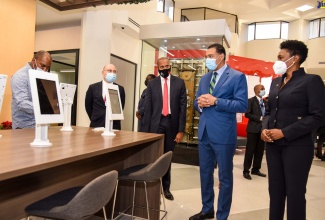 Prime Minister, the Most Hon. Andrew Holness (second right), examines the  new iPad tablets customers will use in the banking hall of the renovated Scotiabank Centre in downtown Kingston, which the Prime Minister reopened, on Thursday (December 10).  With the Prime Minister (from left) are Opposition Spokesman on Finance, Planning and the Public Service, Julian Robinson; Chairman, Scotia Group Jamaica, Jeffrey Hall; President and Chief Executive Officer, Scotia Group Jamaica, David Noel and Executive Vice President, Retail Banking, Scotiabank, Audrey Tugwell Henry.