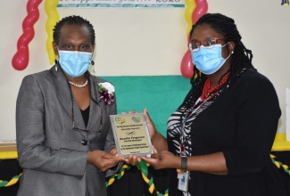 Parish Manager for the Manchester Health Services, Sandia Chambers-Ferguson (left), receives an award for 24 years of service to the Manchester Health Services from the Southern Regional Health Authority Regional Non-Communicable Disease (NCD) Coordinator, Dr. Yasine Hanna. 