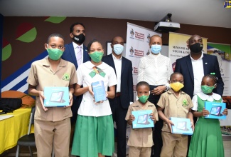 Minister of Education, Youth and Information, Hon. Fayval Williams (second right, background), looks on as students of Mona Heights Primary show off the tablets they received during a ceremony held at the institution in St. Andrew on Tuesday (December 8). A total of nine devices were handed over under the Ministry’s ‘One Laptop or Tablet Per Child’ initiative. Also sharing the moment (in background, from left) are Executive Director, Tourism Enhancement Fund (TEF), Dr. Carey Wallace; Deputy Executive Director and Senior Lecturer, Mona School of Business and Management, University of the West Indies (UWI), Dr. Andrew Spencer; and Acting Principal, Mona Heights Primary, Alex Hepburn.  

