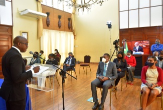 Minister of Housing, Urban Renewal, Environment and Climate Change, Hon. Pearnel Charles Jr. (left), addresses the small in-person audience at a virtual post-Cabinet press briefing on Wednesday (December 9). Also pictured in the front row (second right) is State Minister in the Ministry of Education, Youth and Information, Hon. Robert Morgan.

