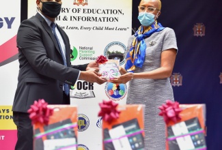 Minister of Education, Youth and Information, Hon. Fayval Williams (right), accepts a tablet from General Manager, Berger Paints Jamaica, Shashi Mahase, during his visit to the Ministry's offices in Kingston, on Friday (December 18). The occasion was the ANSA McAL Foundation's (Berger Paints) presentation of 100 tablets for students islandwide, in support of the Ministry's ‘One Laptop or Tablet Per Child Initiative’.                               
