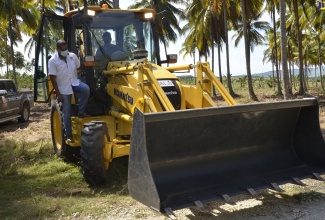 Minister of Agriculture and Fisheries, Hon. Floyd Green (left), aboard the backhoe that was handed over to the St. Elizabeth Office of the Rural Agricultural Development Authority (RADA) during a ceremony held at the Holland Estate in St. Elizabeth on Friday (January 15).