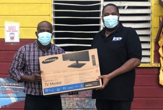 Principal of the Grateful Hill Primary and Infant School in St. Catherine, George Moodie (left), receives one of three computers donated to the school by Chairman of Micro- Financing Solutions, Dino Hines (right), during a ceremony at the school recently.