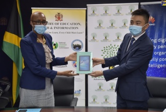 Minister of Education, Youth and Information, Hon. Fayval Williams (left), accepts a tablet from Regional Executive of Huawei Technologies, Bo Zhou, during a ceremony for the handover of 500 devices on Thursday (December 7) at the Ministry’s National Heroes Circle location in Kingston. The donation is in support of the Ministry's  ‘One Laptop or Tablet Per Child’ initiative.