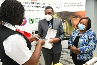 Minister of State, Ministry of Education, Youth and Information, Hon. Robert Nesta Morgan (centre), presents a resident of Homestead Place of Safety (left) with a tablet during the handover of 200 devices, donated by the Ministry to the Child Protection and Family Services Agency (CPFSA),  on Tuesday (January 12), at the agency’s office in Kingston. Observing is Chief Executive Officer,  CPFSA, Rosalee Gage Grey. The devices were donated under the Ministry’s ‘One Laptop or Tablet pQAer Child’ initiative.  

