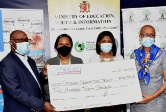 Minister of Education, Youth and Information, Hon. Fayval Williams (right), accepts a cheque valued at $250,000 from Chairman, Jacden Group of Companies, Councillor Dennis Gordon (left), to purchase tablet computers for students, during a presentation ceremony at the Minister’s Heroes Circle offices in Kingston on January  25. Also sharing in the moment (from second left) are Acting Chief Education Officer in the Ministry, Dr. Kasan Troupe; and Director of Donor and Partnership Management at the National Education Trust (NET), Latoya Harris.

