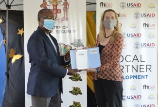 Director, Office of Citizen Security at the United States Agency for International Development (USAID), Shannon Stone (right), presents a tablet to pastor of the Flanker Adventist Church, Alpheus Smith (left), during a ceremony at the Flanker Primary and Junior High School in St. James, on Friday, February 5.