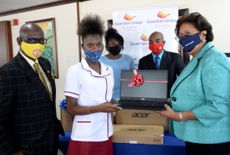 Minister of Local Government, Hon. Desmond McKenzie (left), observes as Student, Denham Town High School, Careen Wilson, is given a laptop computer by Executive Insurance Agent, Guardian Life, Fay Hutchinson (right), during a ceremony held at the Ministry's Hagley Park Road offices on February 3. Others participating (from third left) are Teacher, Denham Town High School, Shanique Hamilton and Principal, Denham Town High School, Donovan Hunter. Minister McKenzie accepted the donation of tablets from Guardian Life’s Trafalgar Road Branch. The gift of 12 laptops is intended for the Denham Town High School in the constituency of West Kingston.