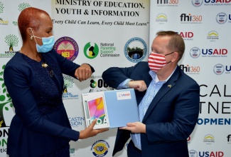 Minister of Education, Youth and Information,  Hon. Fayval Williams (left), knocks elbows with Charge d’Affaires, United States Embassy in Jamaica, John McIntyre, on Tuesday (February 2), at the Ministry, at Heroes Circle, in Kingston, after accepting samples of computers to be distributed among 10 schools.

