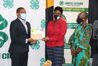 Minister of Agriculture and Fisheries, Hon. Floyd Green (left) presents a certificate of award to winner of the Jamaica 4-H Clubs Backyard Family Garden Challenge, Shaneka Wallace-Graham from St. James, at the virtual award ceremony on Thursday (February 25). At right is Resident Representative, United Nations Development Programme (UNDP) Multi-Country Office in Jamaica, Denise Antonio. Mrs. Wallace-Graham received a cash prize of $60,000, seedlings, and gardening tools.