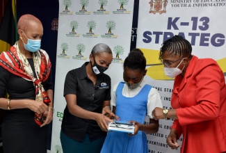 Education, Youth and Information Minister, Hon. Fayval Williams (left), observes as Business Administration Manager, Stone Plus Limited, Saccherine Chin (second left), assists grade-five Lyssons Primary, student, Nathallia Crumbie (third left), in using her new tablet.  Principal of the school, Evette Bonfield Beecher, looks on. The occasion was the handover of 100 tablets donated by Stone Plus Limited under the ‘One Laptop or Tablet Per Child’ initiative, at the Ministry’s Heroes Circle offices in Kingston on Wednesday (February 24).

